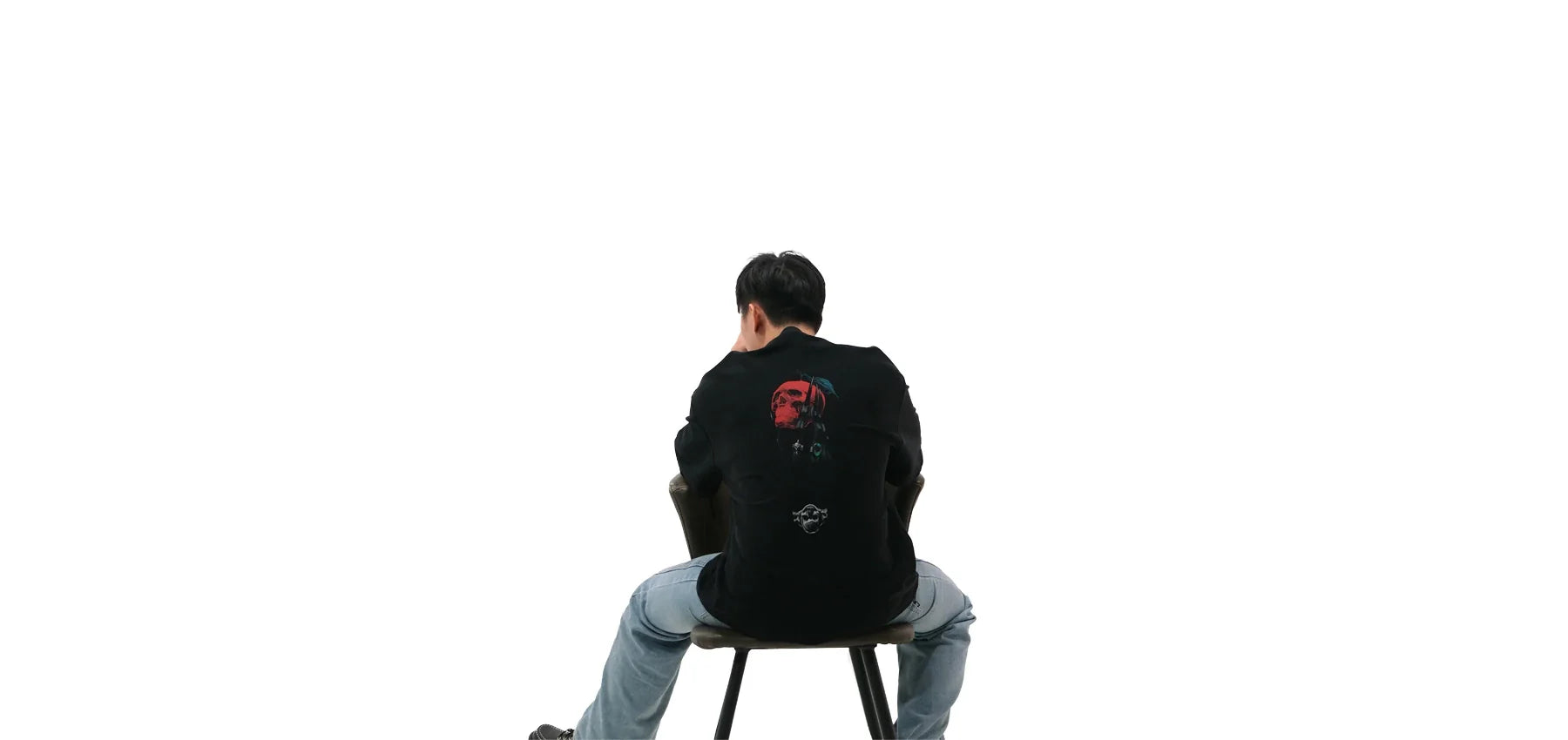 Back view of oversized black NO1 Apparels anime t-shirt, subtle anime streetwear inspired by Death Note featuring Ryuk holding an apple, worn by a seated male model.