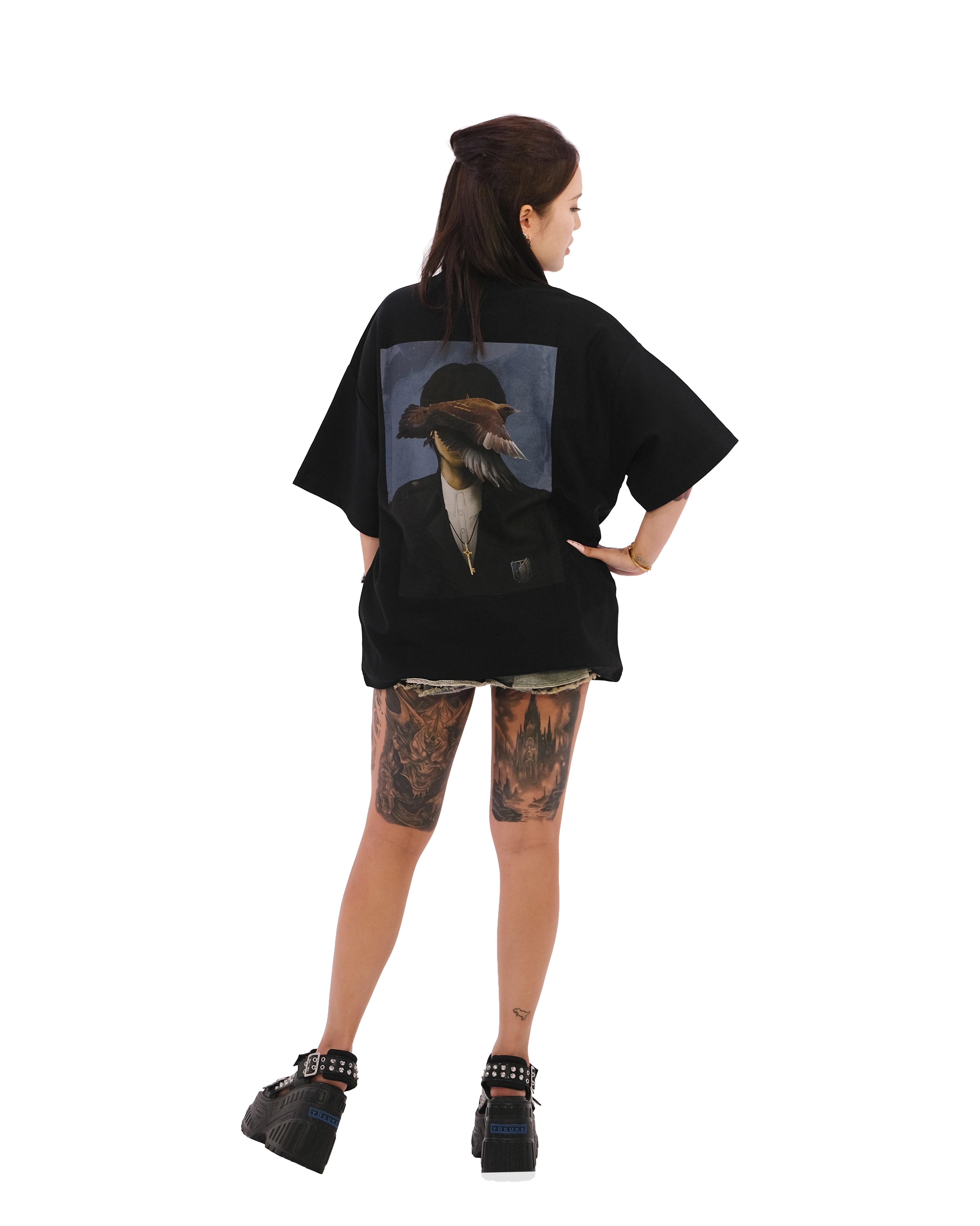 Back view of oversized black NO1 Apparels anime t-shirt, subtle anime clothing inspired by Attack on Titan, Son of Grisha design featuring minimalist graphic inspired by Magritte's The Son Of Man Painting infused with Attack on Titan elements, worn by female model.