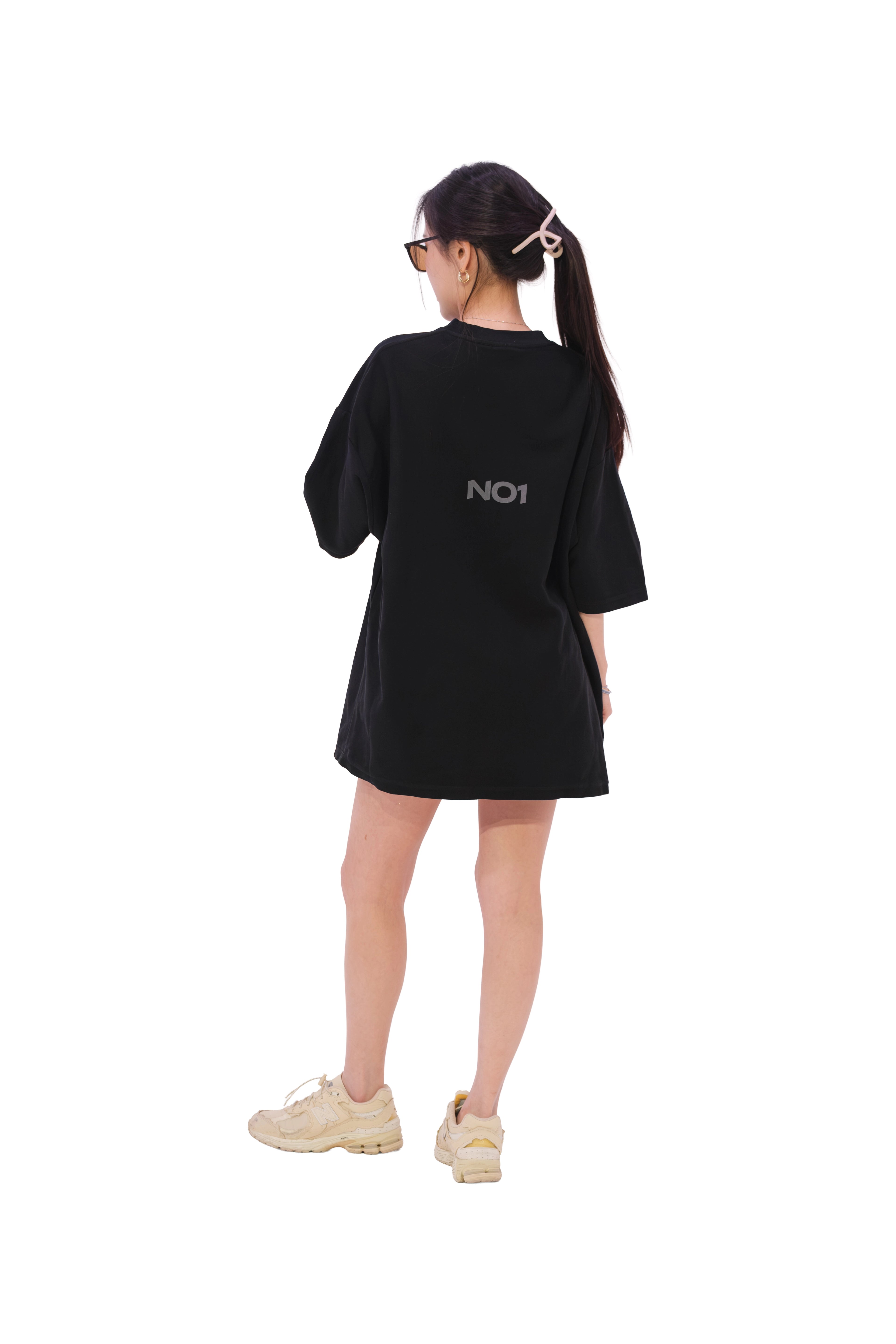 Back view of black oversized subtle anime t-shirt featuring a minimalist NO1 logo at the upper center. Premium anime streetwear from NO1 Apparels, worn by female model.