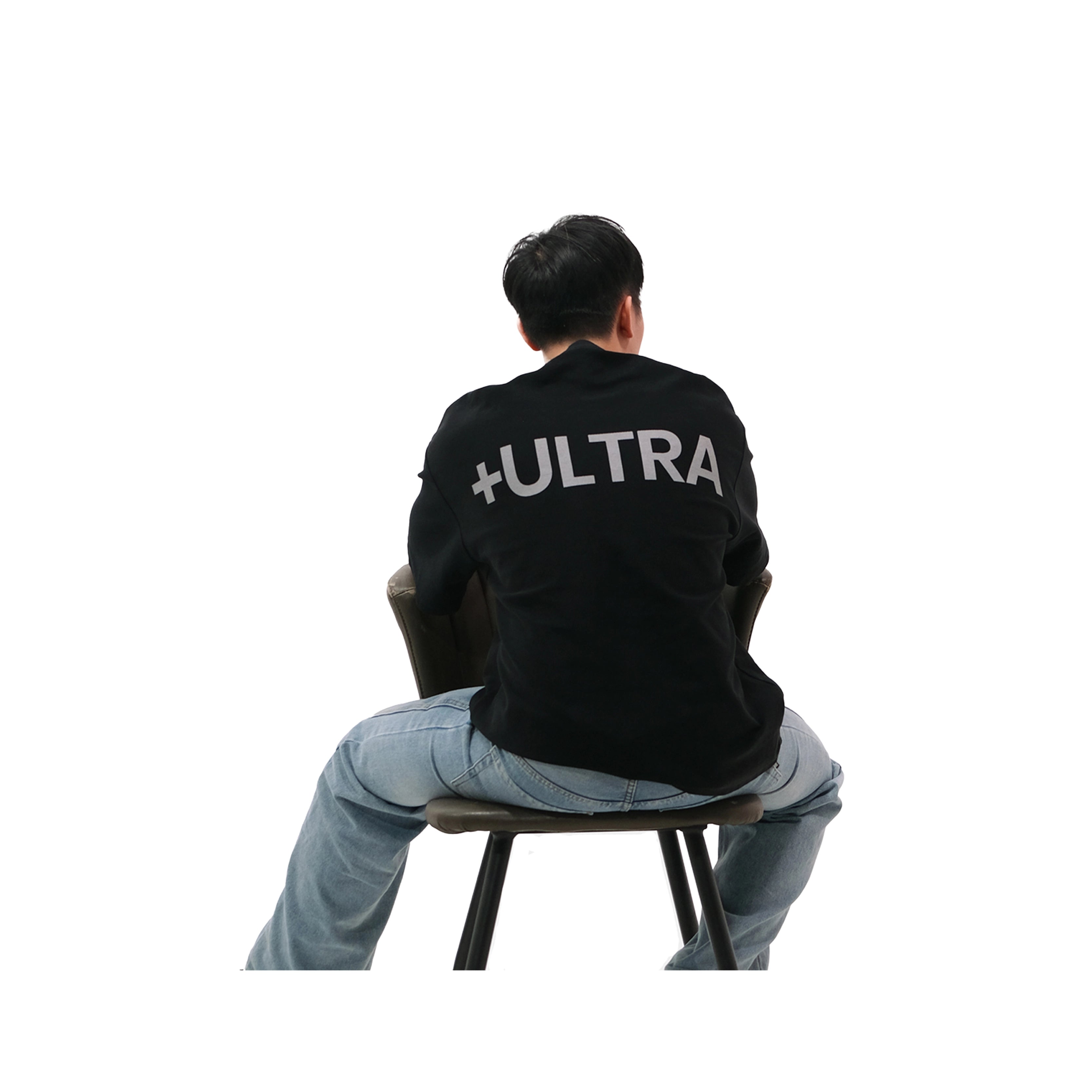 Back view of oversized black NO1 Apparels anime t-shirt, subtle anime streetwear inspired by My Hero Academia PLUS ULTRA design with bold typography, worn by male model sitting on chair.